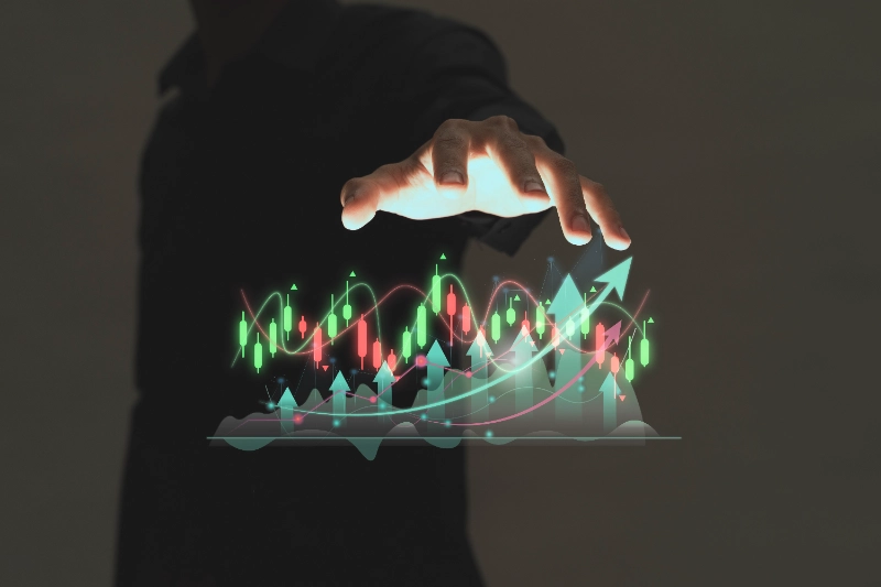 Mano sobrevolando un gráfico financiero holográfico con velas alcistas, bajistas y flechas ascendentes de crecimiento.