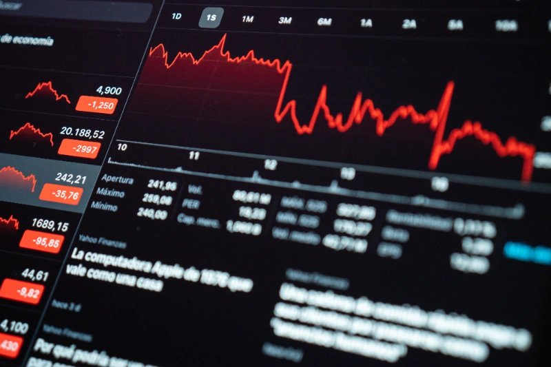 Pantalla con gráficos bursátiles en rojo que muestran caídas y pérdidas financieras en el mercado.