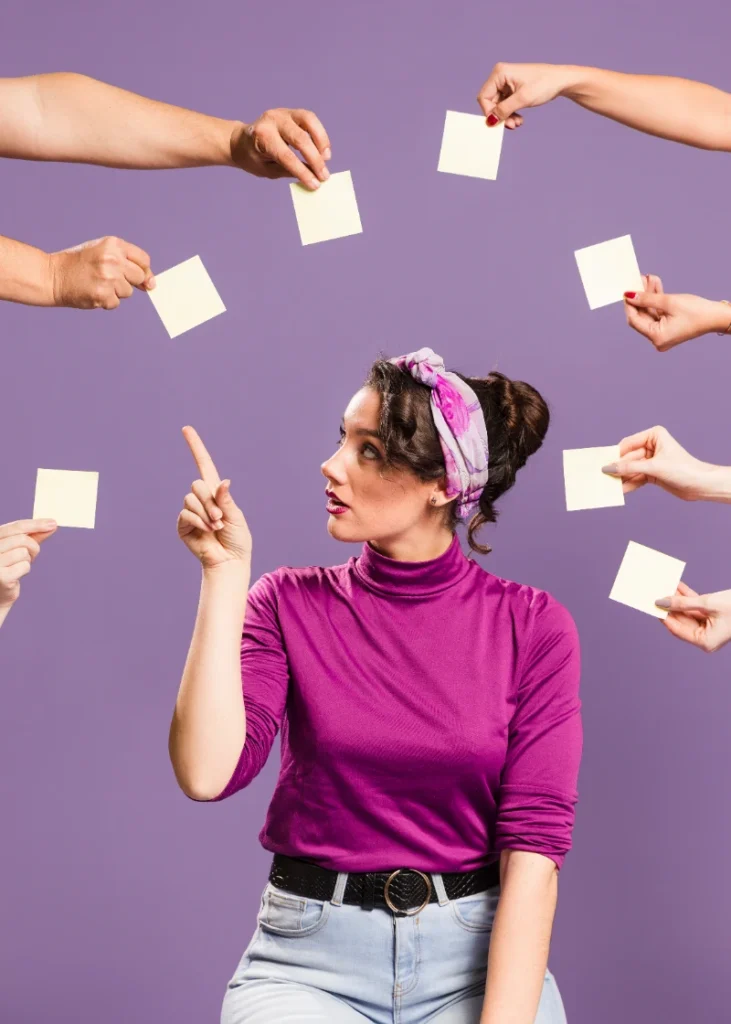 Una mujer con camisa morada y cinta en el cabello apunta hacia arriba mientras varias manos a su alrededor le ofrecen notas adhesivas amarillas sobre un fondo morado.